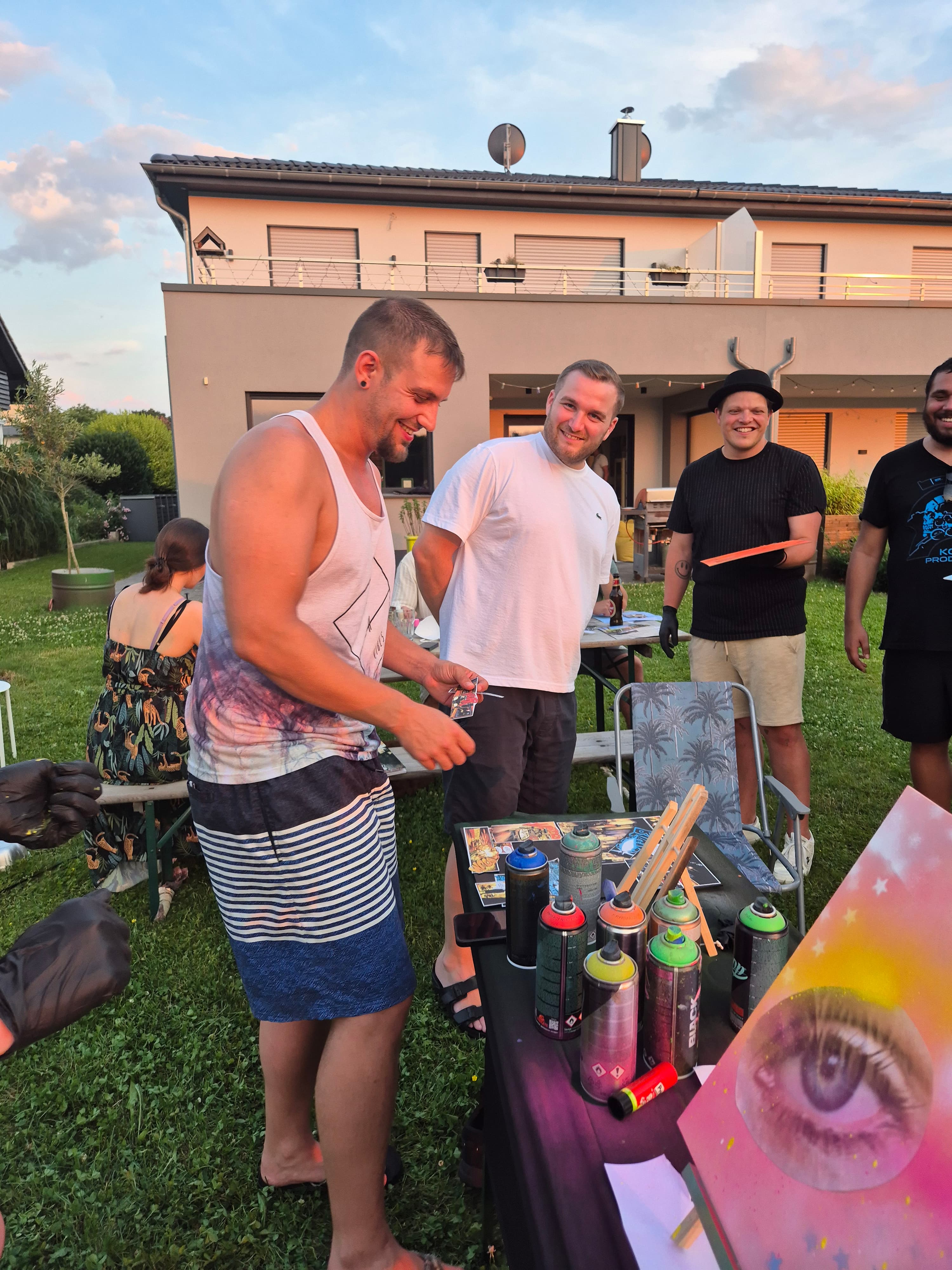 Workshopgruppe steht um ein farbiges Augenmotiv und gemeinsam genutzte Spraydosen
